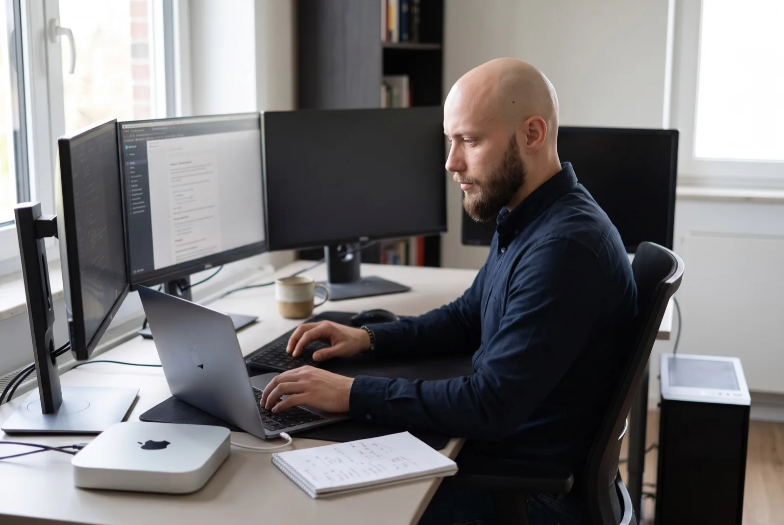 KI-generiertes Foto: Floris Waller Litjens am aufgeräumten Schreibtisch mit drei Monitoren, MacBook und Mac mini.